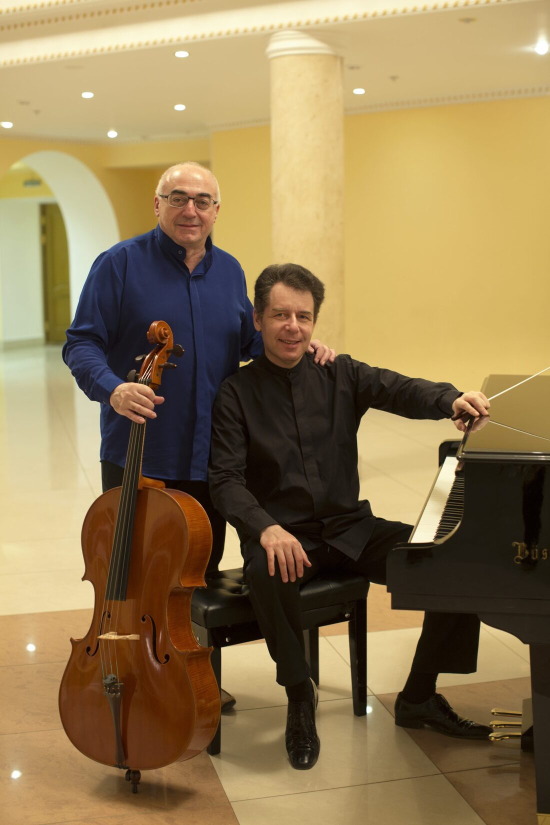 Alexander Kaganovsky standing with his cello beside a pianist seated at a grand piano